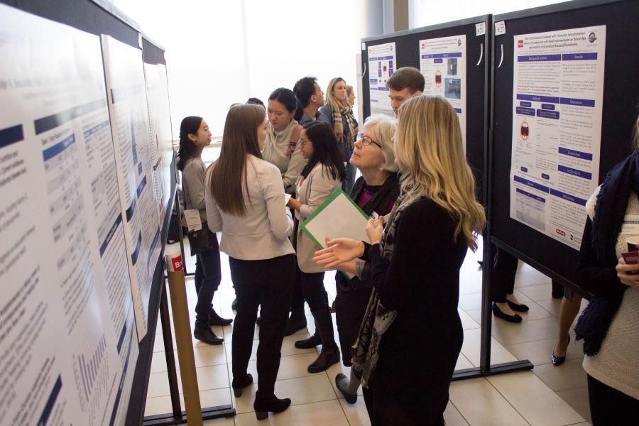 People gather around poster presentations at research day