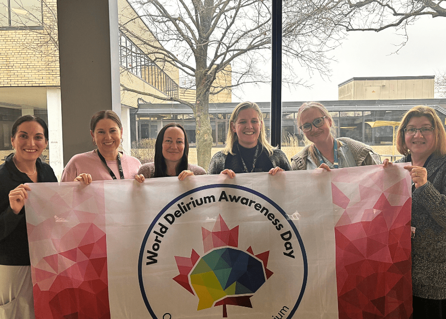 Niagara Health staff hold up the World Delirium Day flag
