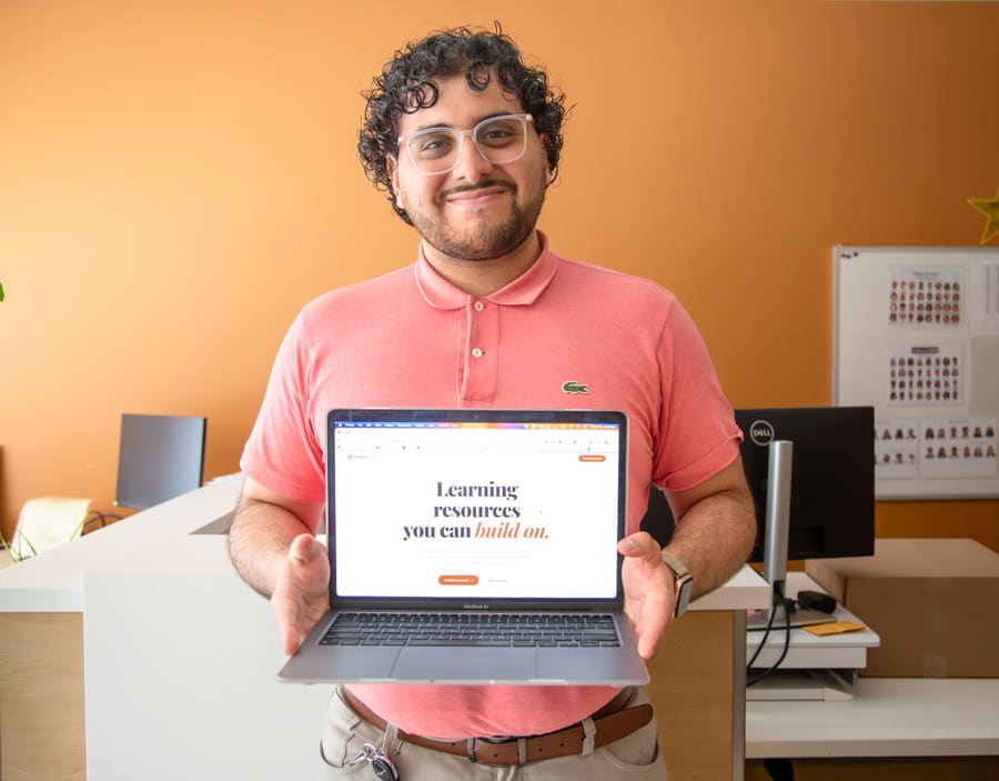 Medical learner Amr Almasri holds a laptop open to his webpage