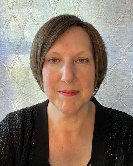 A headshot of a woman with a bob cut hairdo, wearing black. 