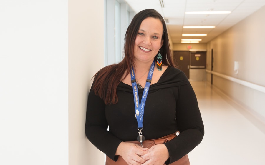 An Indigenous woman stands in a hospital hallway, smiling for the camera