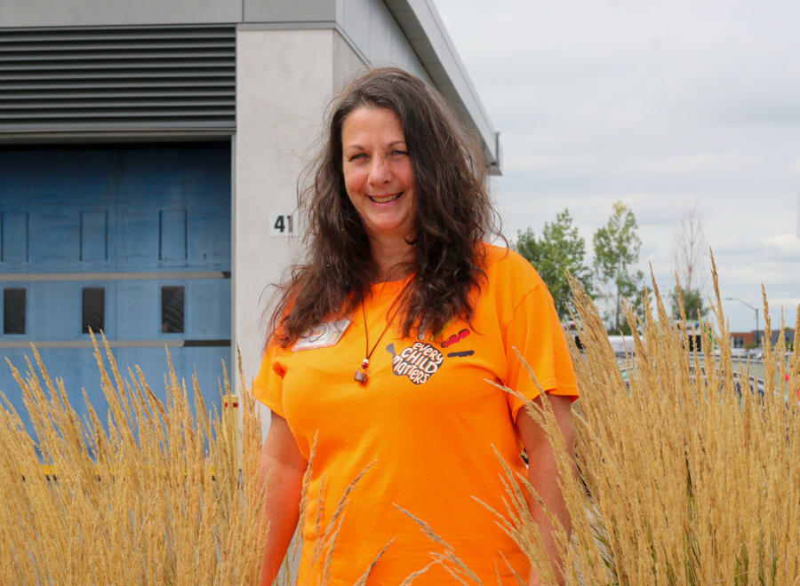 A woman wearing an orange t-shirt that reads Every Child Matters smiles for the camera