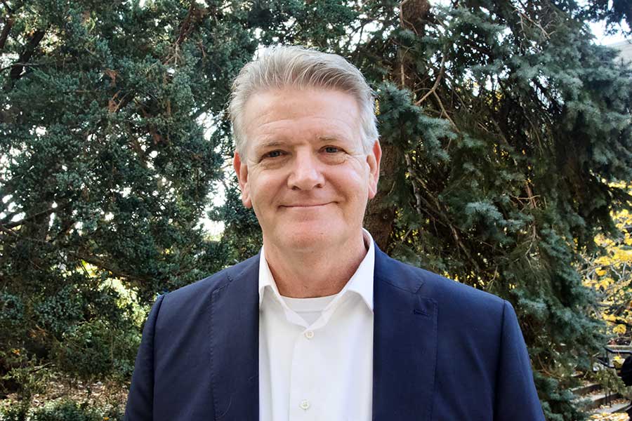 A close-up photo of a man with grey hair who is smiling into the camera