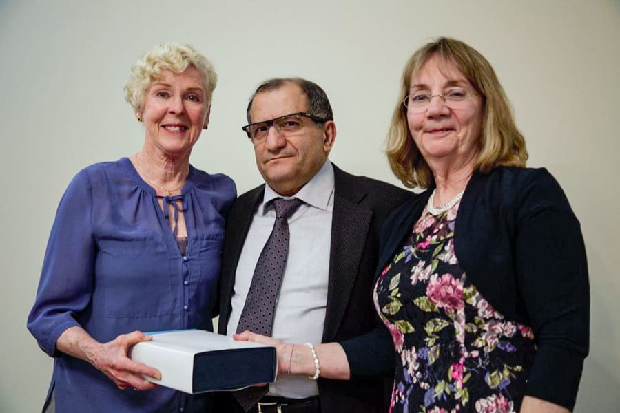 Three people, two women and one man, stand together for a photo. Their eyes are wet with tears.