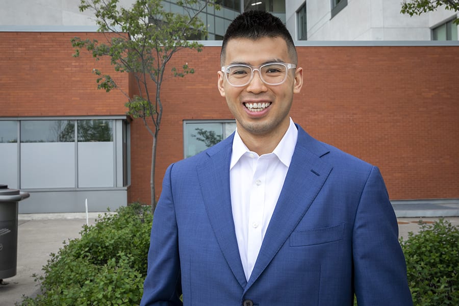 Dr. Ben Tam. A man in a blue suit with funky glasses smiles for the camera