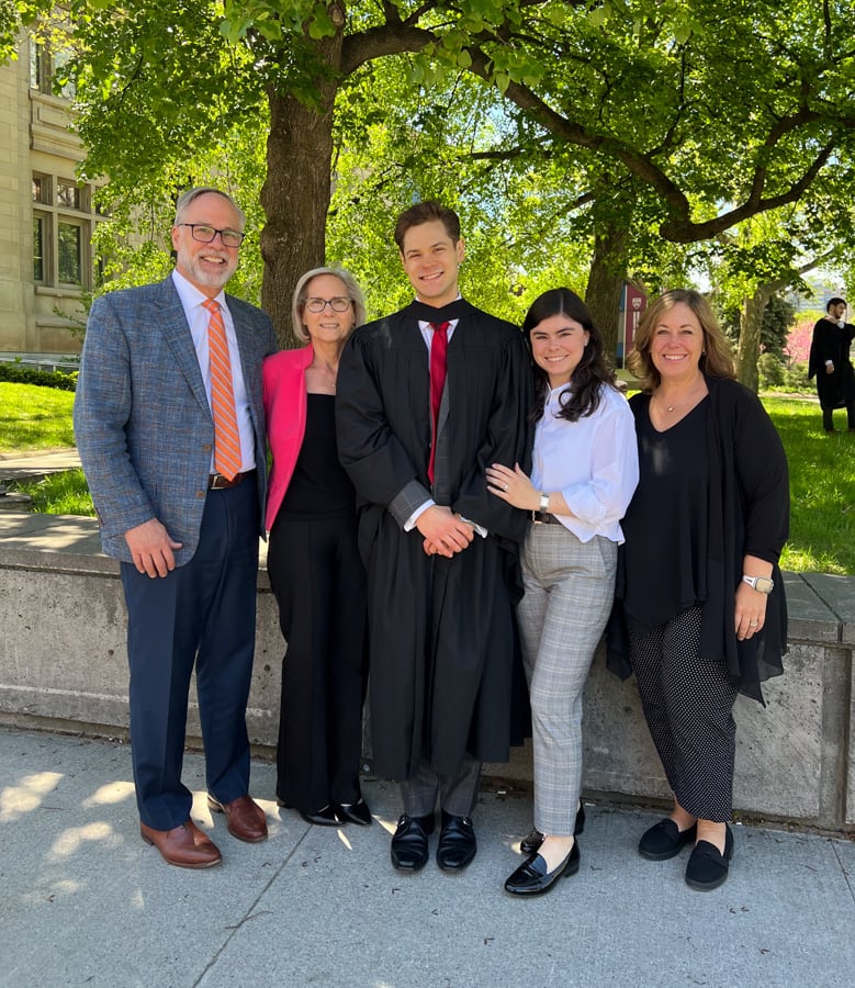Grant Sweeny with his family on graduation day, standing outside under a tree.