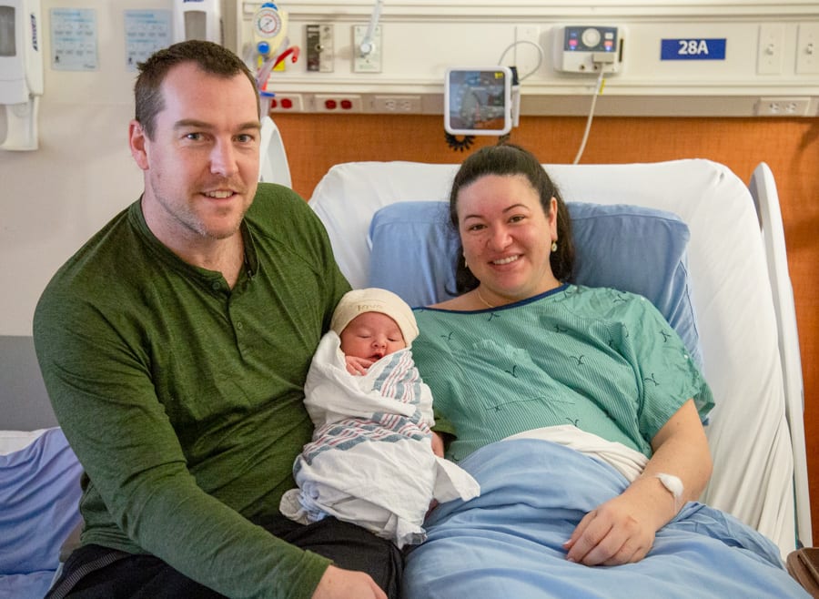 Nick and Kimberly Forma hold baby Clark while resting in a hospital room.