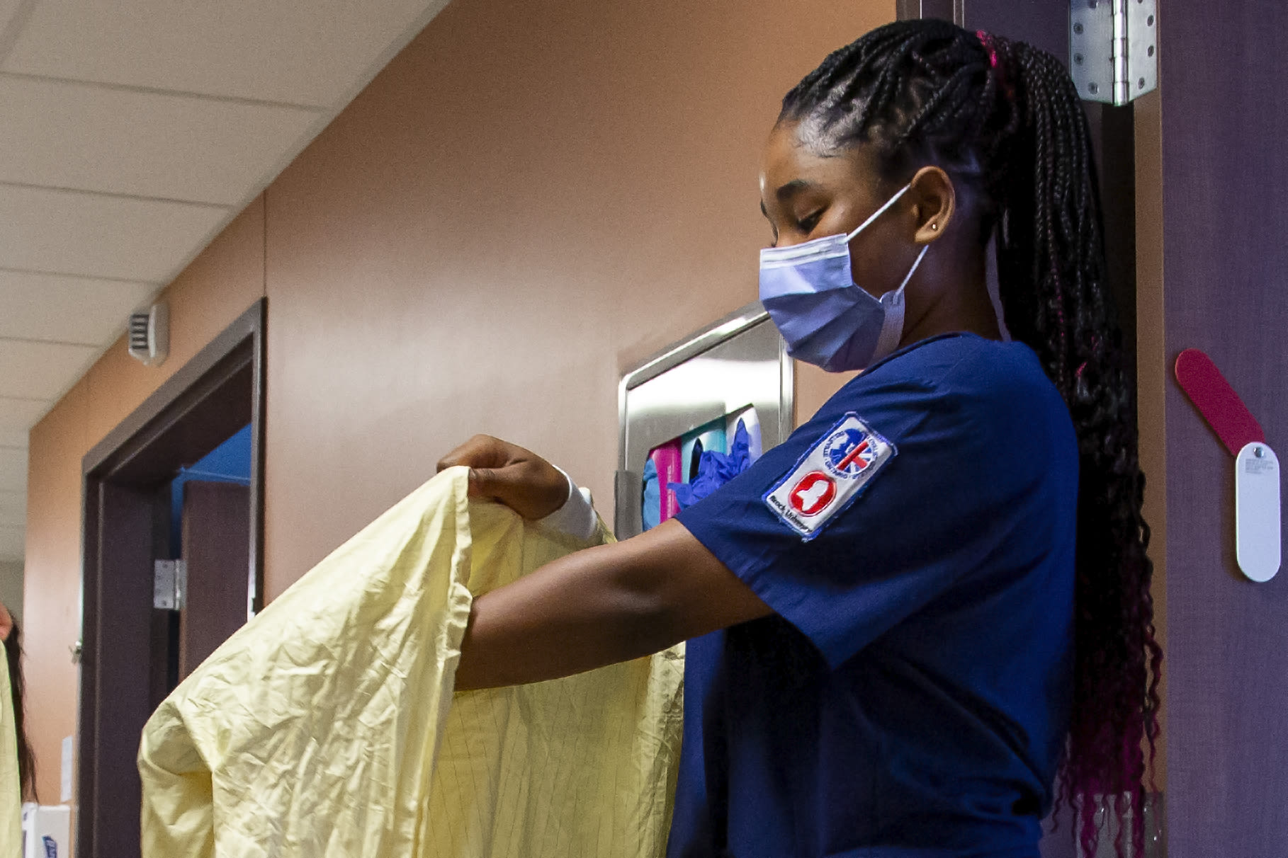 Oreoluwa Majekodunmi puts on personal protective equipment (PPE).