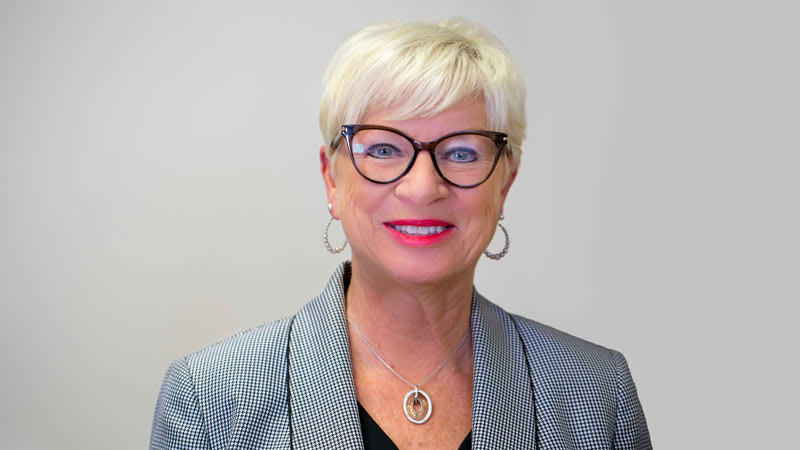 Patty Welychka. A woman in glasses with short blonde hair smiles for the camera.