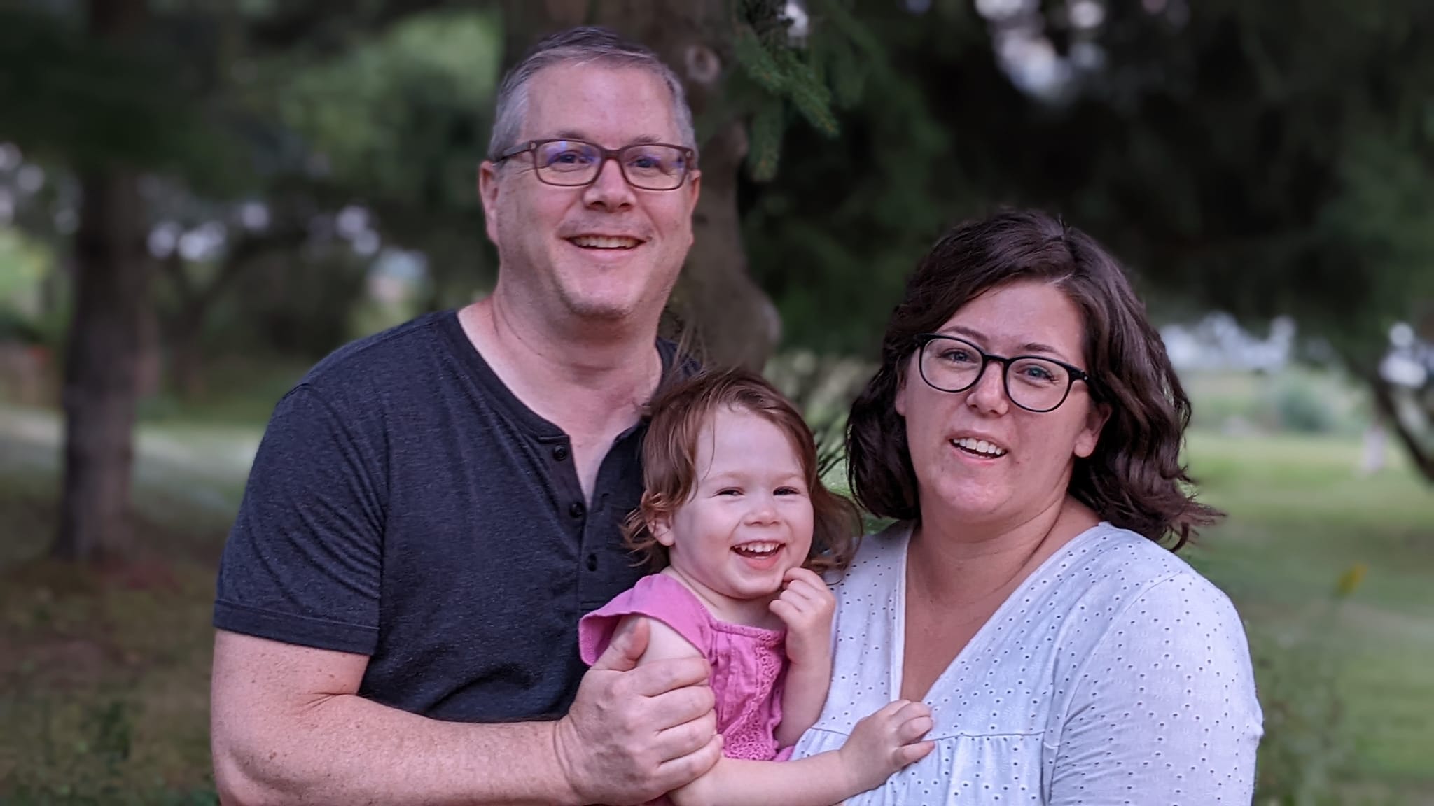 A family portrait of a man and woman holding their young daughter