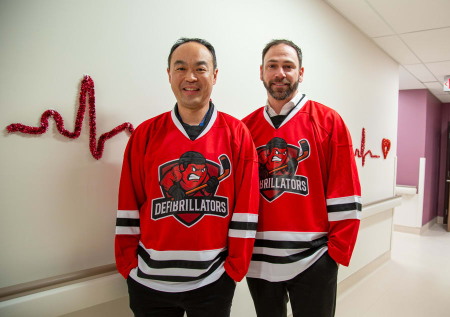 Richard Sit and Patrick Raymond, founding members of the Defibrillators, in their jerseys with a lifeline in the background.