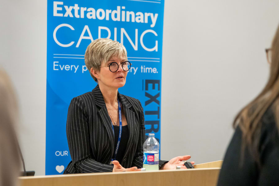 A woman stands at a podium speaking to someone. 