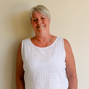 A woman with short, ash-blonde hair smiles for the camera