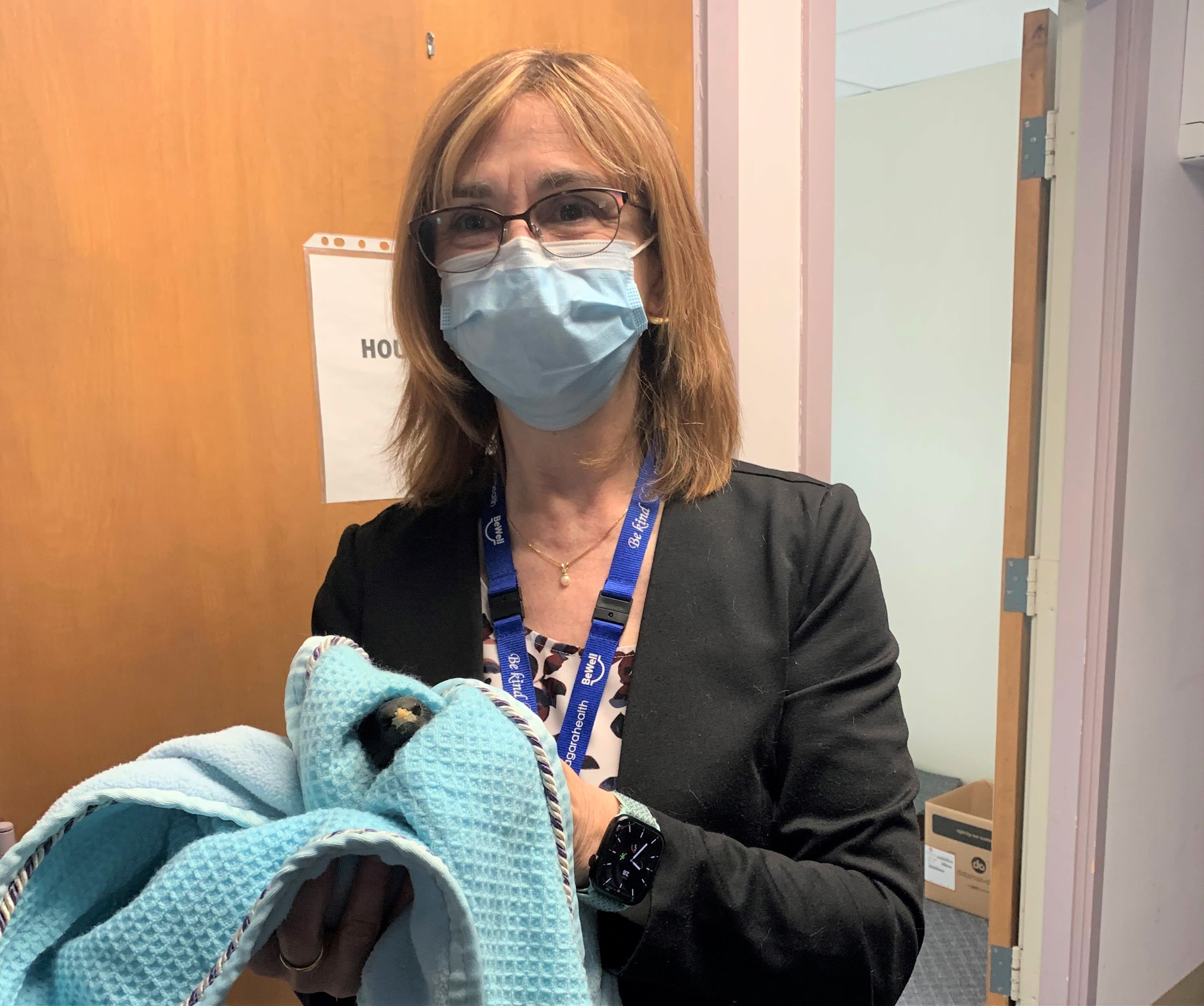 Teri Haeni. A woman in glasses and a surgical mask holds a bird. 