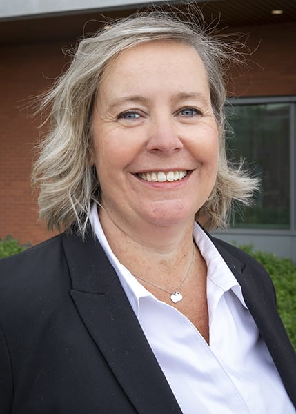 A woman in a white shirt and black blazer smiles for the camera