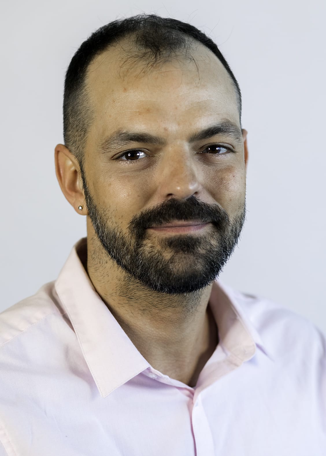 A man with dark hair and beard smiles for the camera