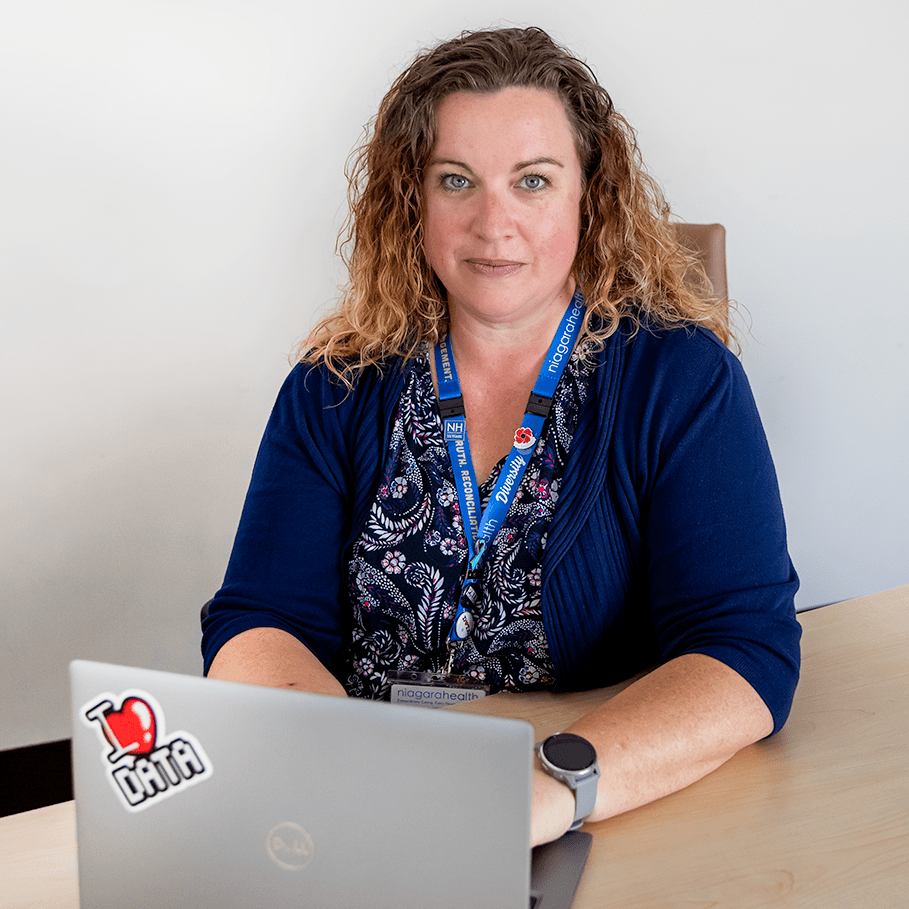 A woman sits at her desk with her hands on her laptop.