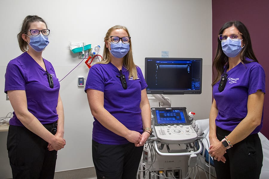 Three women gather around an ultrasound machine