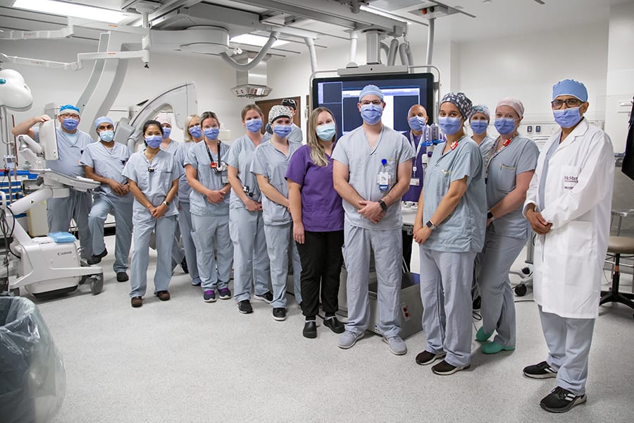 A group of people stands in a hospital room with diagnostic imaging equipment