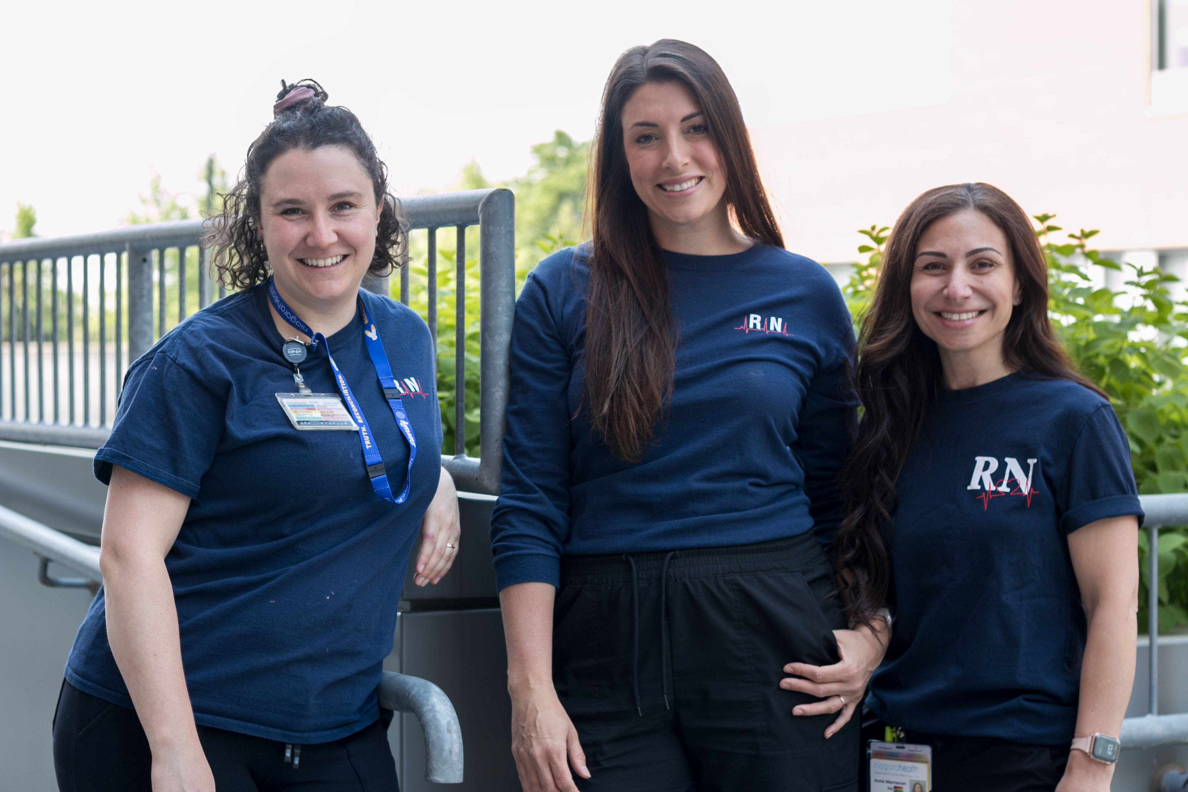 Three women wearing RN t-shirts stand outside on a sunny day