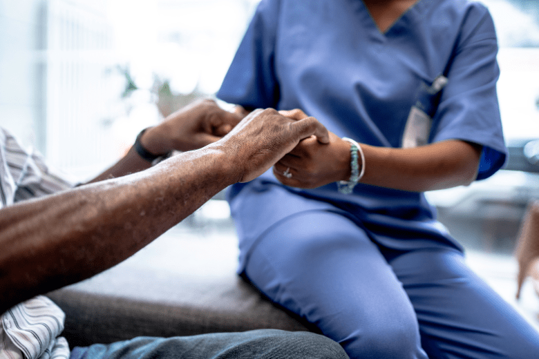 Healthcare worker holding a patient's hands