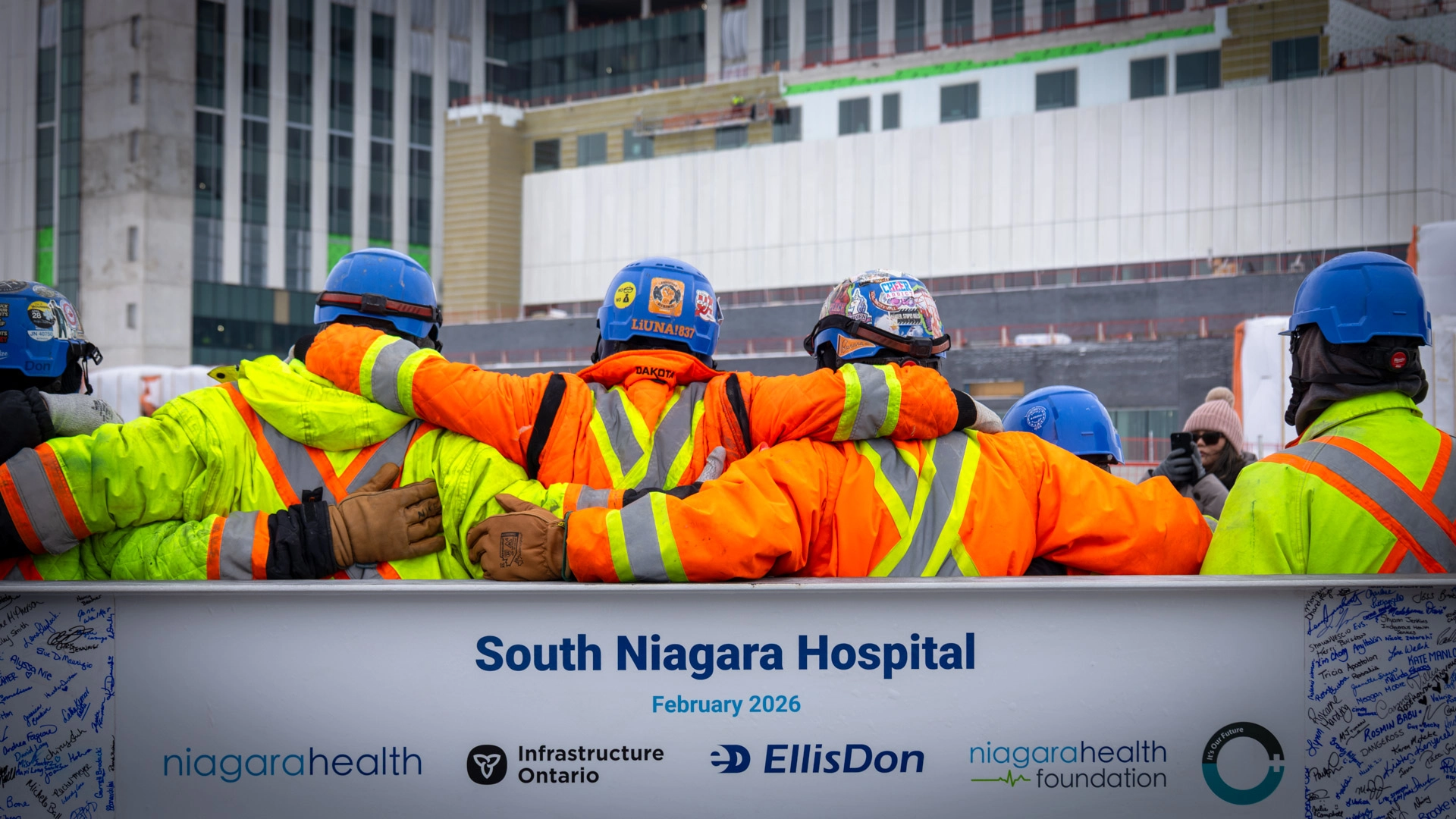 South Niagara Hospital construction site team standing in front of the last structural beam
