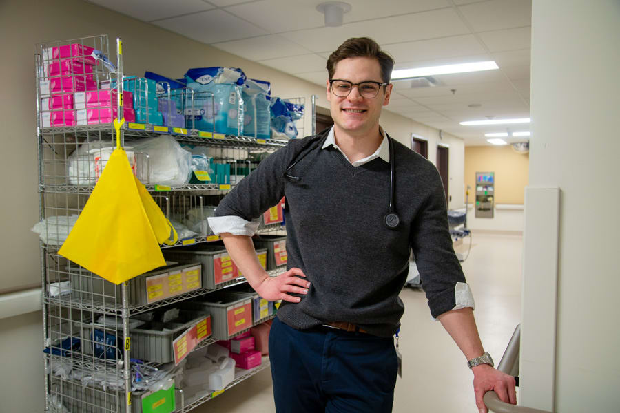 Grant Sweeny stands in front of a cart of medical supplies. 