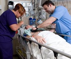 two nurses look over a patient in a bed